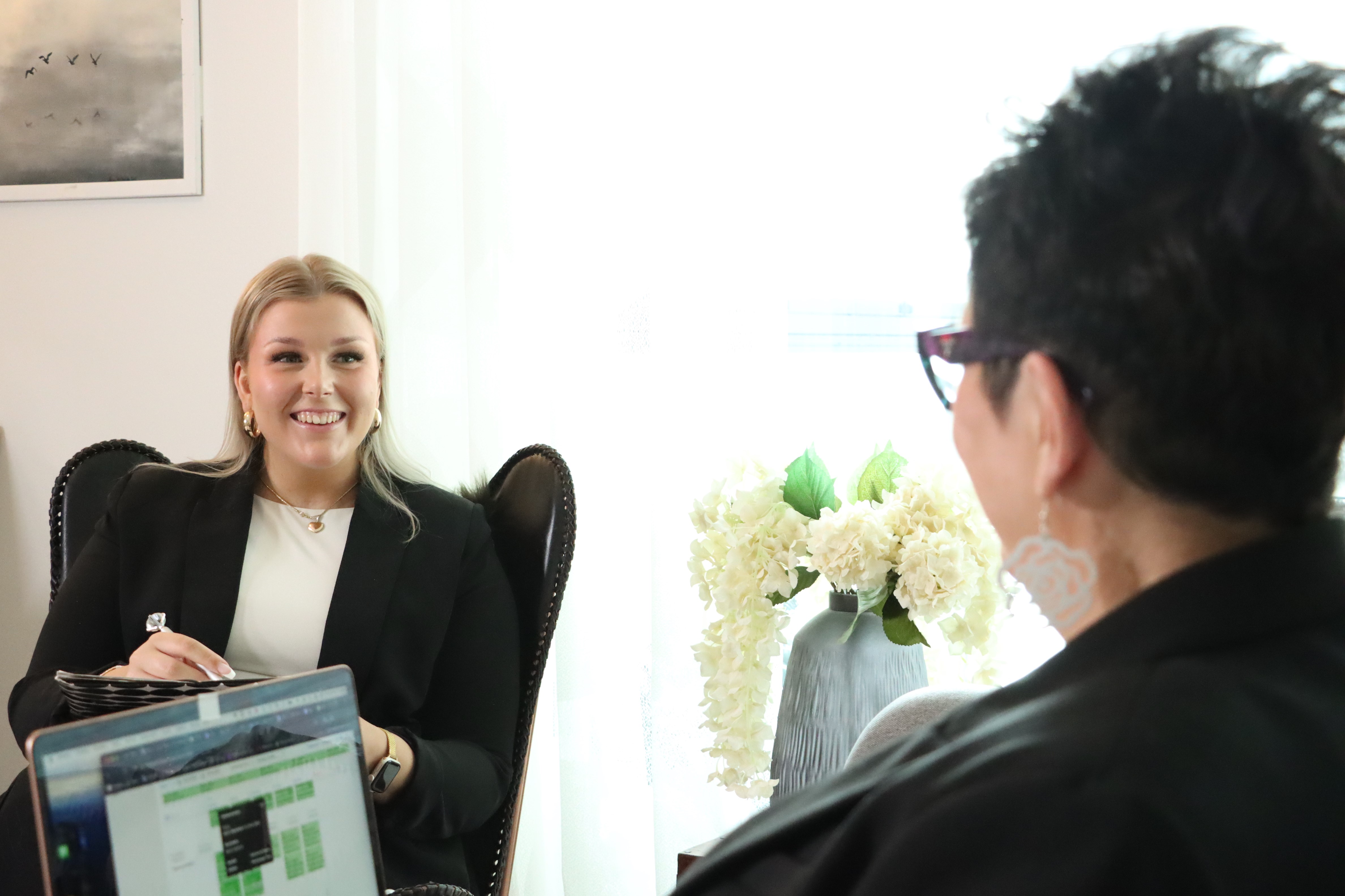 Kuvituskuva. Karita Alanko istuu työkone sylissään ja juttelee toisessa tuolissa olevan Petriina Alangon kanssa.