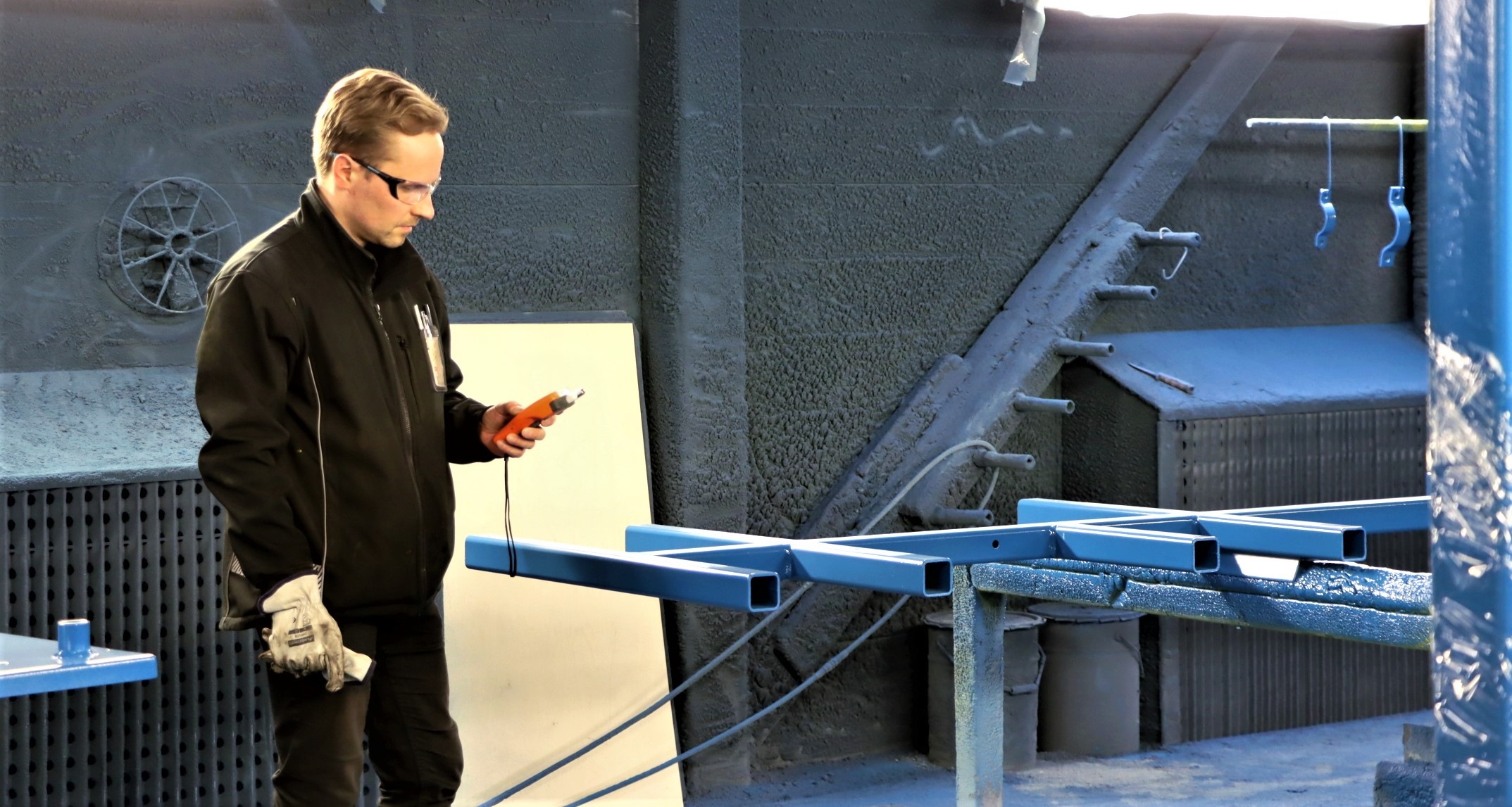 Petri Saarijärvi tutkii kädessään olevaa laitetta tehtaassa